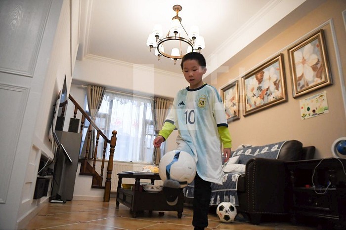 (200316) -- CHANGSHA, March 16, 2020 (Xinhua) -- Lu Shu, Wu Yu’s son, juggles the ball with his new jersey on at home in Changsha, central China’s Hunan Province on March 16, 2020. Wu Yu is a nurse from the third batch of medical teams from Xiangya Hospital to the coronavirus-hit Hubei Province. After a busy day on duty on March 8, Wu was asked if she had a wish for Women’s Day, and gave what she felt was an ambitious response. 