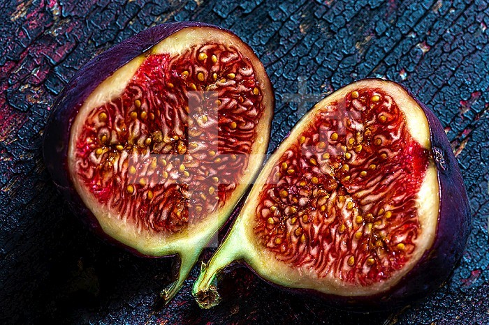 Black fig sliced in half ready to eat close-up top view on tone-on-tone support.