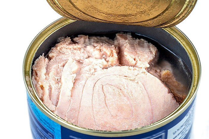 Open tuna can close up top view on white background.