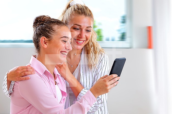 2 friends looking at a photo while bursting out laughing