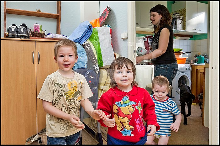 ASE - Childhood Social Assistance. Morgan, 5, Sarah, 3, and Maxence, 2, play in the hallway while their mother is busy preparing breakfast in the kitchen. EDITORIAL USES ONLY.