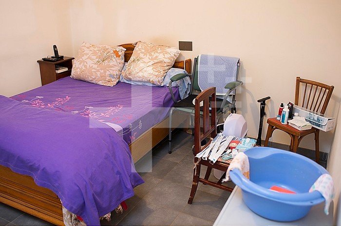 ADMR 62 - Home Help in Rural Areas, Pas de Calais. Muriel, Auxiliary of Social Life (AVS) works at the home of Mr. T. who is severely handicapped by Multiple Sclerosis. Muriel must help her with all the daily tasks. Bedroom with commode near the bed and paramedical equipment.