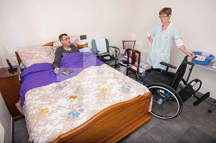 ADMR 62 - Home Help in Rural Areas, Pas de Calais. Muriel, Auxiliary of Social Life (AVS) works at the home of Mr. T. who is severely handicapped by Multiple Sclerosis. Muriel must help her with all the daily tasks. Carer helping a disabled person to bed in his bedroom.