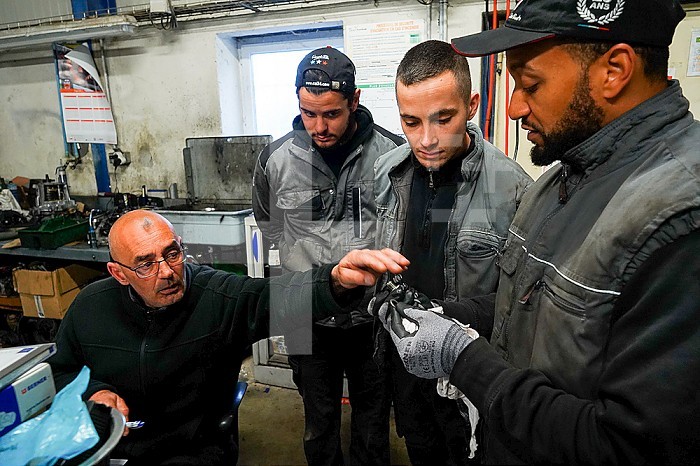 Business immersion of five workers from the mechanical workshop of an ESAT. Under the responsibility of auto mechanic professionals, workers with disabilities are trained in the mechanical profession and work independently in the workshop. Monitor and workers around a mechanical part.