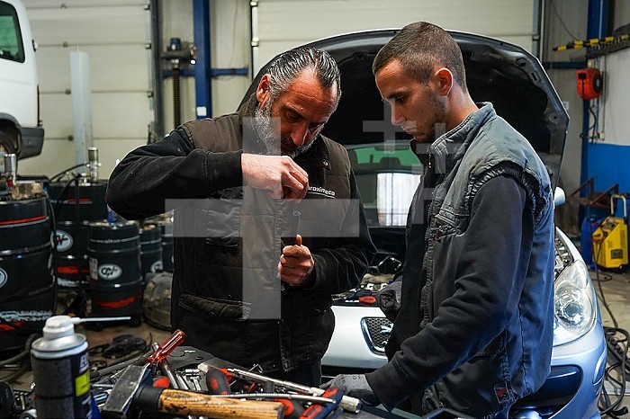 Business immersion of five workers from the mechanical workshop of an ESAT. Under the responsibility of auto mechanic professionals, workers with disabilities are trained in the mechanics profession and work independently in the workshop. A worker with more seniority passes on to a younger worker.